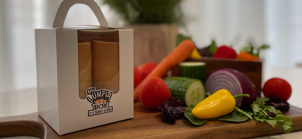 White box with 'My Lumpia Box' branding on a wooden cutting board with vegetables.